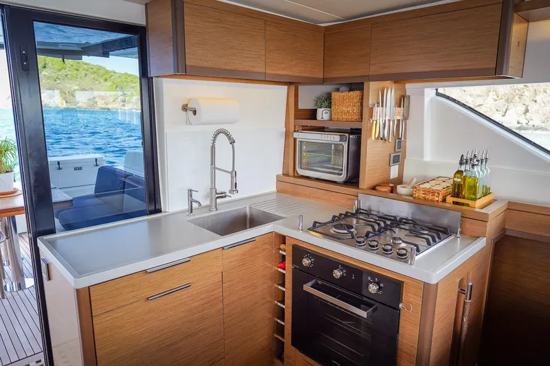 Scuba Doo Yacht Photos Pics Modern kitchen interior on 2021 Lagoon 50 yacht with stove, sink, and ocean view.