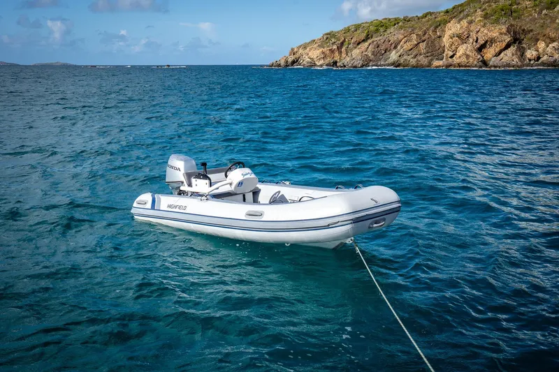 Scuba Doo Yacht Photos Pics Inflatable boat anchored in clear blue water near rocky coastline.