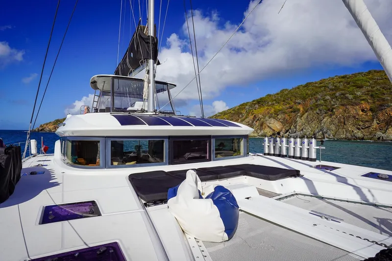 Scuba Doo Yacht Photos Pics 2021 Lagoon 50 catamaran sailing near rocky coastline under blue sky.