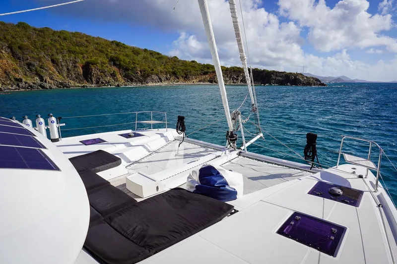 Scuba Doo Yacht Photos Pics 2021 Lagoon 50 catamaran sailing near lush coastline under blue skies.