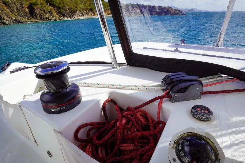 Scuba Doo Yacht Photos Pics Cockpit view of 2021 Lagoon 50 sailboat with ropes and winch, near scenic coastline.