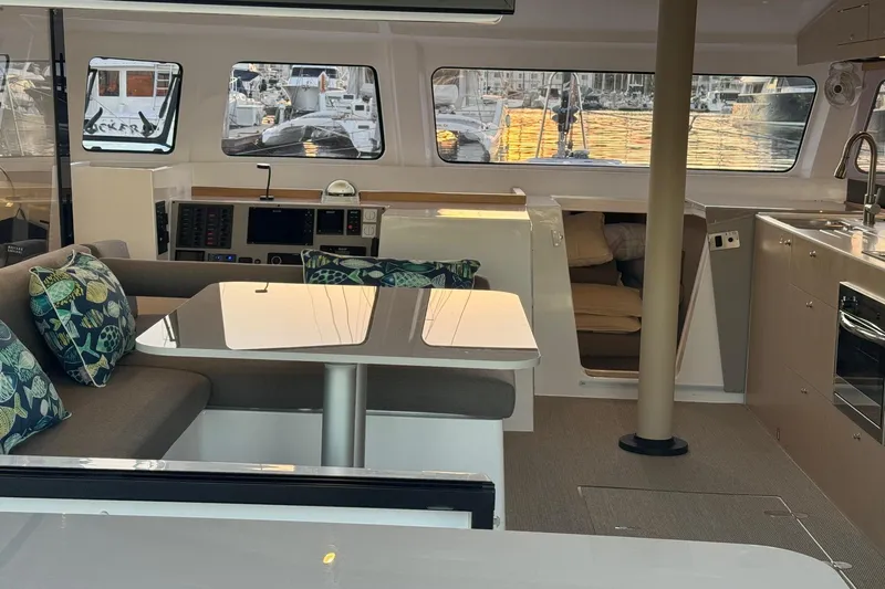 Keizan Yacht Photos Pics Interior of 2023 NEEL 43 yacht with modern seating, table, and kitchen area.