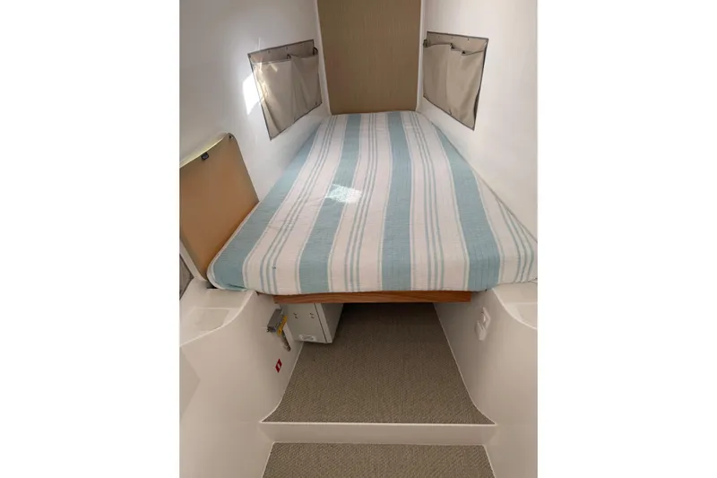 Keizan Yacht Photos Pics Cozy cabin bed in 2023 NEEL 43, featuring striped bedding and storage pockets.