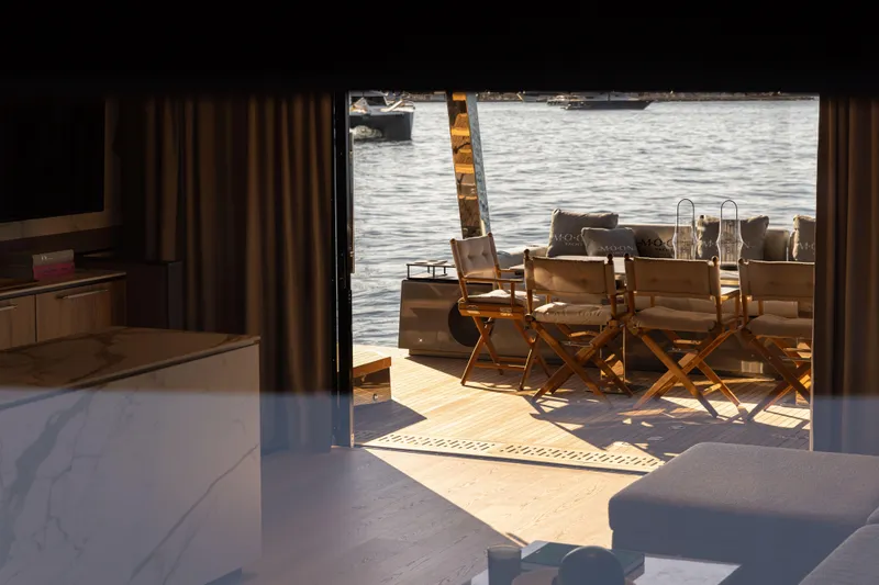  Yacht Photos Pics Luxurious yacht interior with outdoor seating, Moon 65 model, 2025, overlooking serene water.