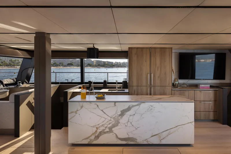  Yacht Photos Pics Luxurious yacht interior with marble kitchen island, wooden cabinets, and waterfront view. Moon 65, 2025 model.