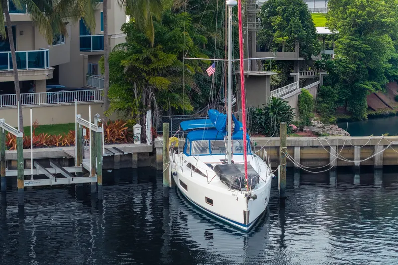 Siman H Yacht Photos Pics 2020 Beneteau Oceanis 46.1 yacht docked by waterfront homes, surrounded by lush greenery.