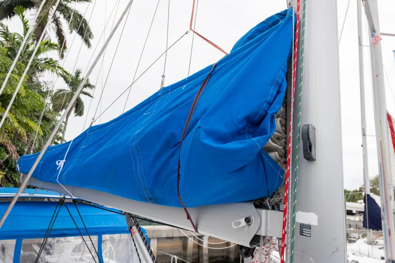 Siman H Yacht Photos Pics 2020 Beneteau Oceanis 46.1 sailboat with blue sail cover, docked near palm trees.