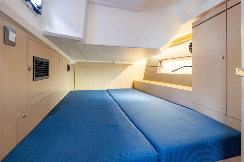 Siman H Yacht Photos Pics Interior cabin of 2020 Beneteau Oceanis 46.1 yacht with blue bedding and wooden cabinetry.