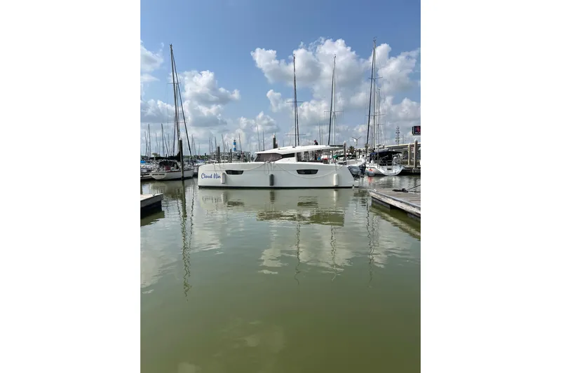 Cloud Nine Yacht Photos Pics 2020 Fountaine Pajot Astrea 42 Catamaran docked in a marina under a blue sky.
