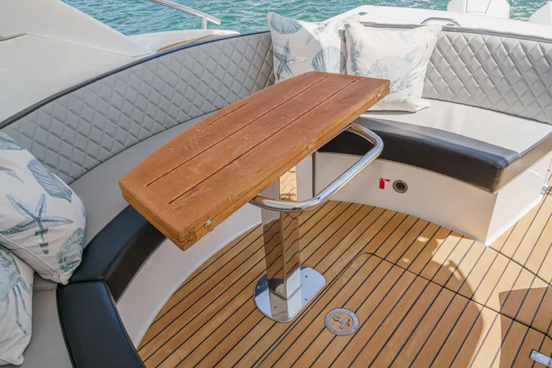 Adamas Yacht Photos Pics Luxury seating area on 2021 Schaefer 400 yacht with wooden table and cushions.