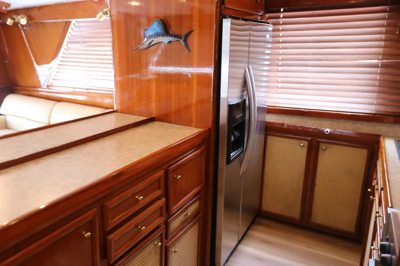 Maple Leaf Yacht Photos Pics 1981 Bertram Convertible yacht interior with wooden cabinetry and stainless steel refrigerator.