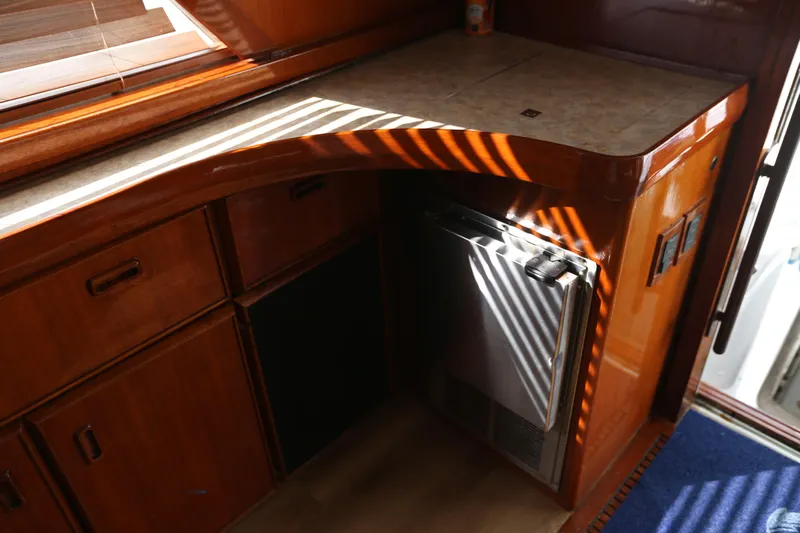 Maple Leaf Yacht Photos Pics 1981 Bertram Convertible interior with wooden cabinetry and compact refrigerator.