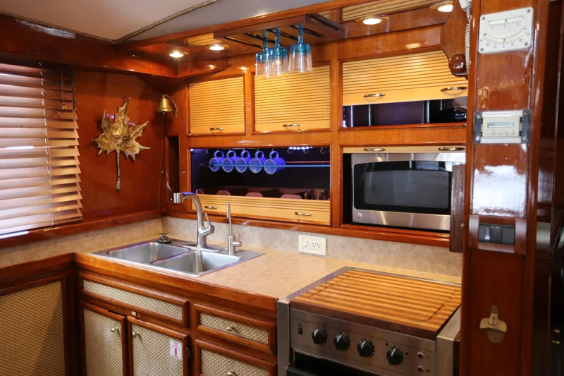 Maple Leaf Yacht Photos Pics 1981 Bertram Convertible yacht kitchen with wooden cabinets, stainless steel sink, and modern appliances.