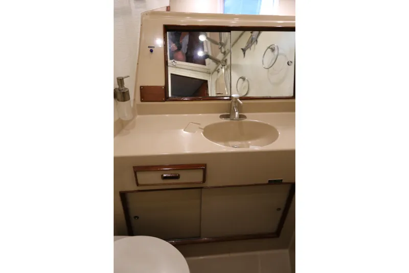 Maple Leaf Yacht Photos Pics 1981 Bertram Convertible yacht bathroom with sink, mirror, and storage cabinet.