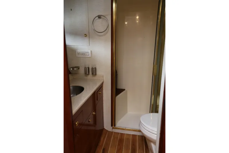 Maple Leaf Yacht Photos Pics 1981 Bertram Convertible yacht bathroom with shower, sink, and wooden flooring.