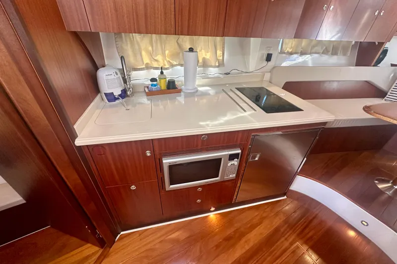 Yacht Photos Pics 2015 Pursuit SC 365i Sport Coupe galley with microwave, cooktop, and wood cabinetry.