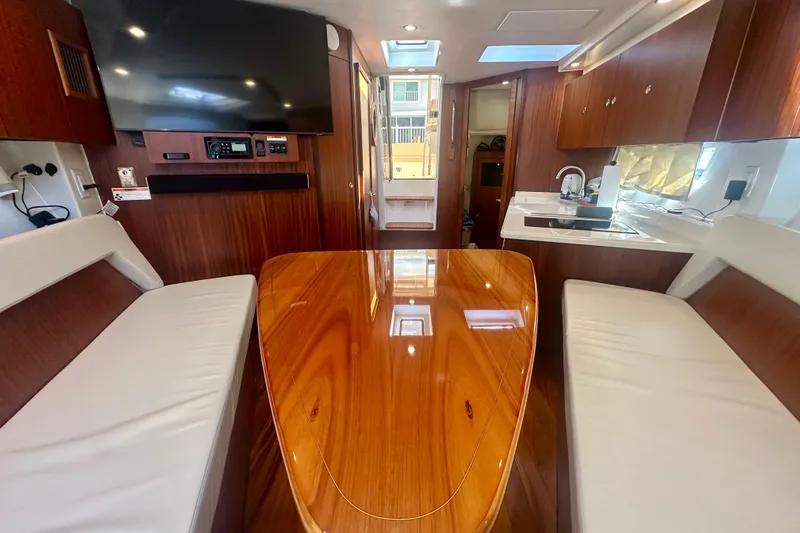  Yacht Photos Pics Luxurious interior of 2015 Pursuit SC 365i Sport Coupe with polished wood table and seating.