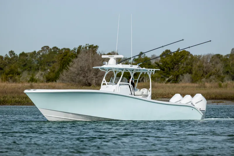  Yacht Photos Pics 2024 Yellowfin 34 Offshore boat cruising on calm water with trees in the background.