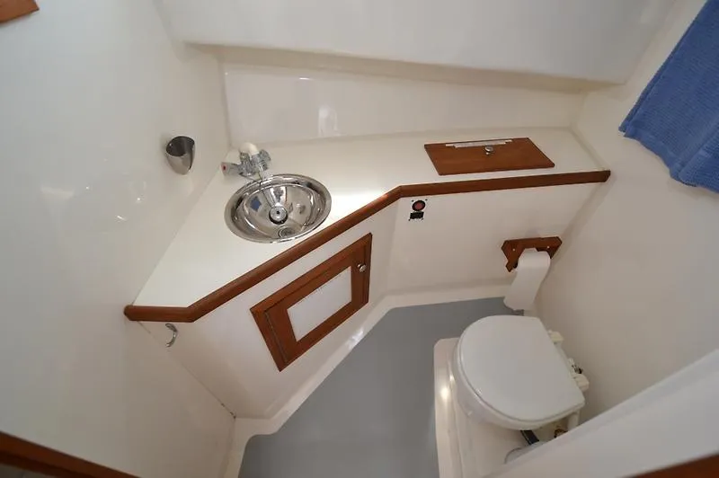Grey Goose Yacht Photos Pics 2002 West Bay 31 boat bathroom with sink, toilet, and wooden accents.