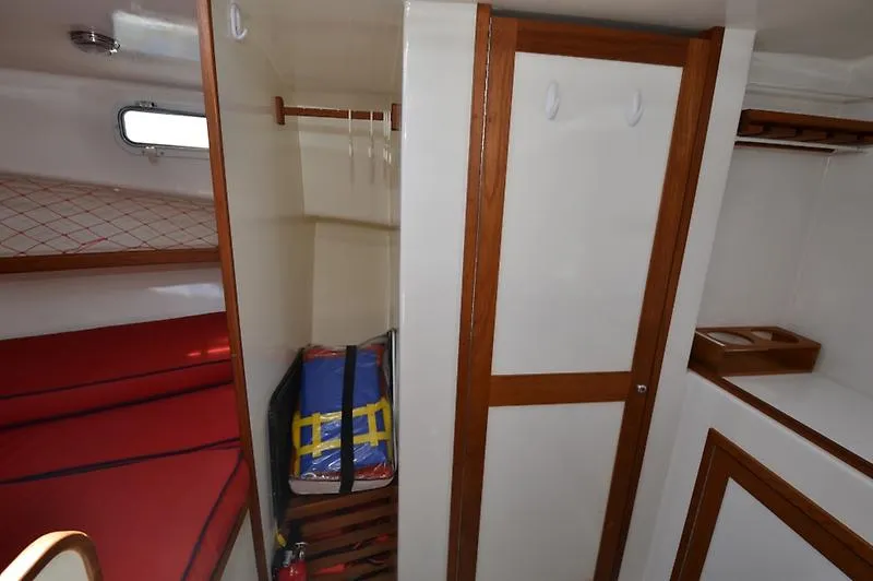 Grey Goose Yacht Photos Pics Interior of 2002 West Bay 31 boat cabin with red bedding and wooden accents.