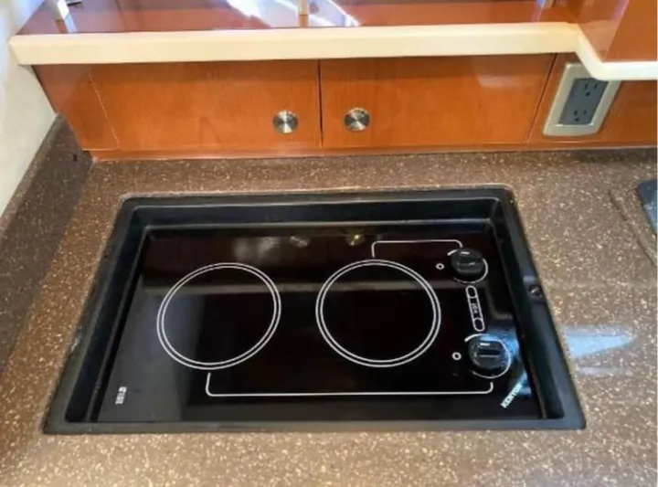  Yacht Photos Pics 2013 Sea Ray 330 Sundancer kitchen with electric stovetop and wooden cabinetry.