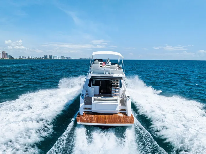 Ferretti 500 Yacht Photos Pics 2024 Ferretti Yachts 500 cruising on open sea, city skyline in background.