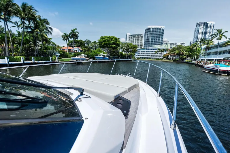 Ferretti 500 Yacht Photos Pics 2024 Ferretti Yachts 500 cruising in a scenic urban waterway with palm trees and skyscrapers.