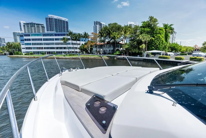 Ferretti 500 Yacht Photos Pics 2024 Ferretti Yachts 500 cruising near modern waterfront buildings and lush greenery.