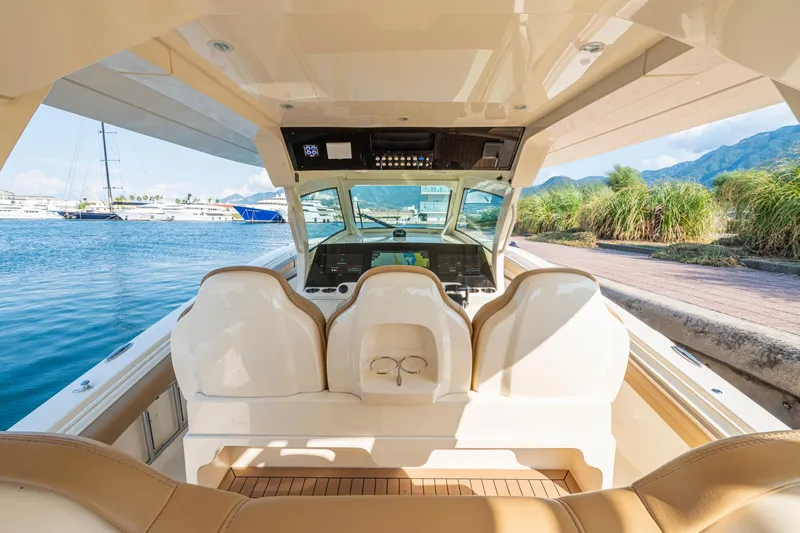  Yacht Photos Pics 2023 Scout 425 LXF boat interior with helm, luxurious seating, and waterfront view.