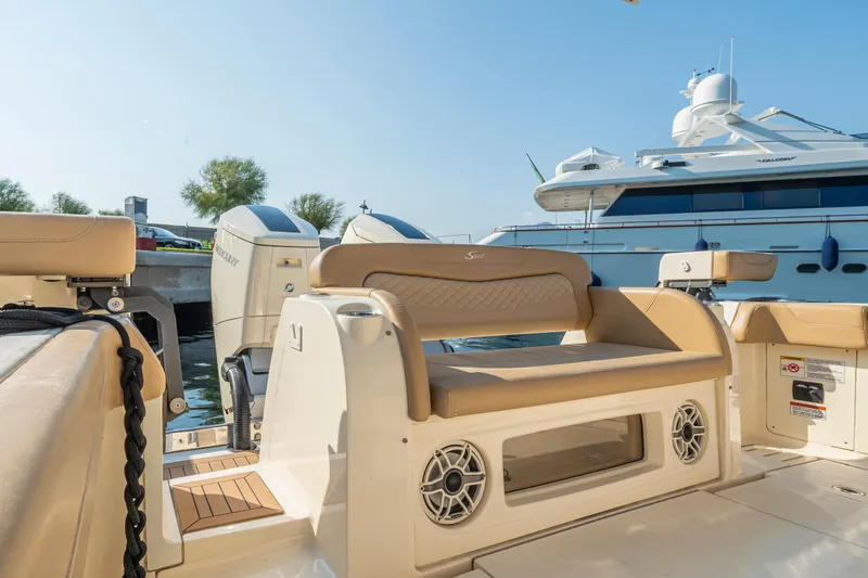  Yacht Photos Pics 2023 Scout 425 LXF boat interior with seating and outboard motors, docked near a yacht.