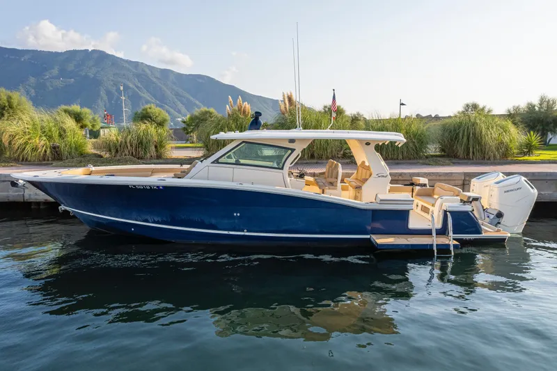  Yacht Photos Pics 2023 Scout 425 LXF boat docked by scenic mountains and lush greenery.