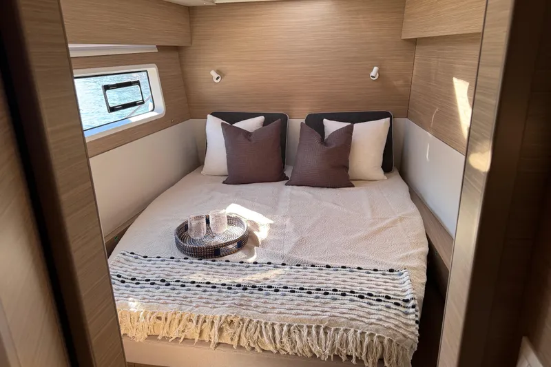  Yacht Photos Pics Luxurious cabin interior of 2026 Lagoon 43 yacht with cozy bed and window view.