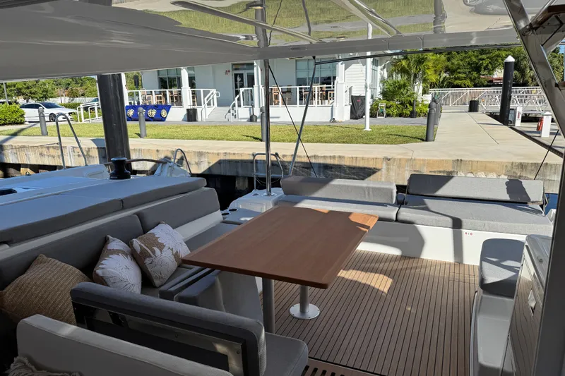  Yacht Photos Pics Luxurious 2026 Lagoon 43 yacht interior with elegant seating and wooden table at dock.