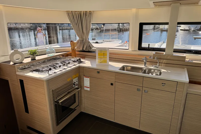  Yacht Photos Pics Modern kitchen interior of 2026 Lagoon 43 yacht with stove, sink, and waterfront view.
