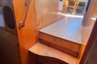 Wooden interior stairs on a 2004 Custom BBL 54' boat, leading to a sunlit cabin.