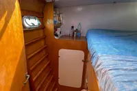 Interior of 2004 Custom BBL 54' boat cabin with wooden finish and blue bedding.
