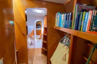 Cozy wooden yacht interior with bookshelves, colorful hammock, and natural lighting. Custom BBL 54', 2004.