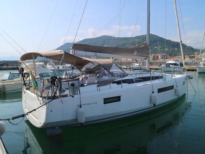  Yacht Photos Pics 2019 Jeanneau Sun Odyssey 410 sailboat docked in marina, scenic mountain backdrop.