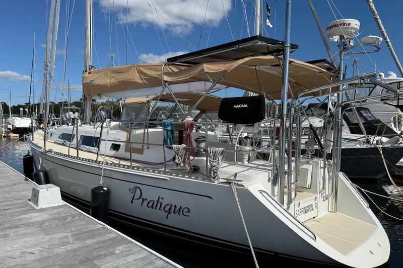 Pratique Yacht Photos Pics Outbound 46 sailboat docked at marina, featuring tan canopy and sleek design, 2012 model.