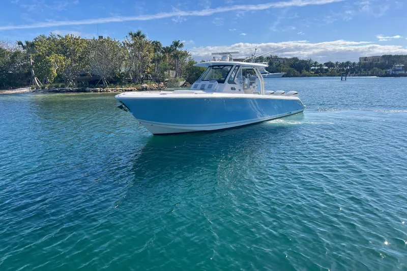  Yacht Photos Pics 2019 Pursuit S 368 Sport boat on clear blue water, sunny day, lush shoreline.