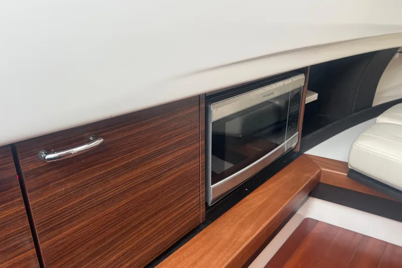  Yacht Photos Pics 2019 Pursuit S 368 Sport interior with microwave and wooden cabinetry.