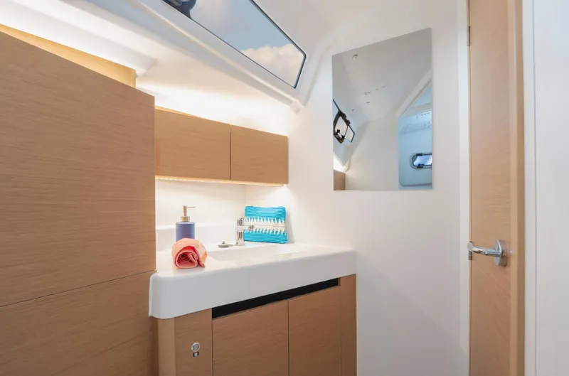  Yacht Photos Pics Modern bathroom interior of 2026 Jeanneau Sun Odyssey 350 yacht, featuring sleek cabinetry and mirror.