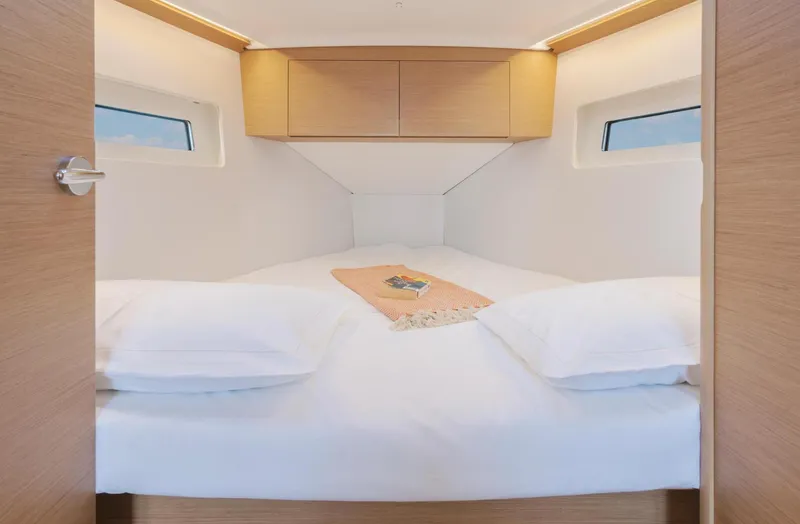  Yacht Photos Pics 2026 Jeanneau Sun Odyssey 350 cabin with cozy bed and wooden cabinetry.
