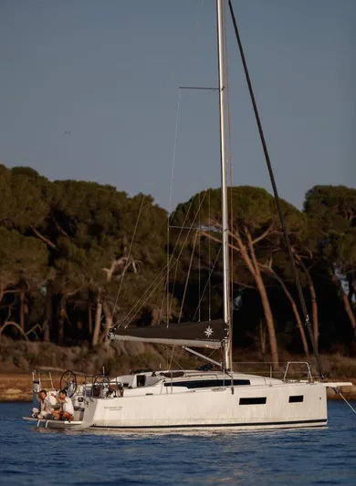  Yacht Photos Pics 2026 Jeanneau Sun Odyssey 350 sailboat on calm water near a forested shoreline.