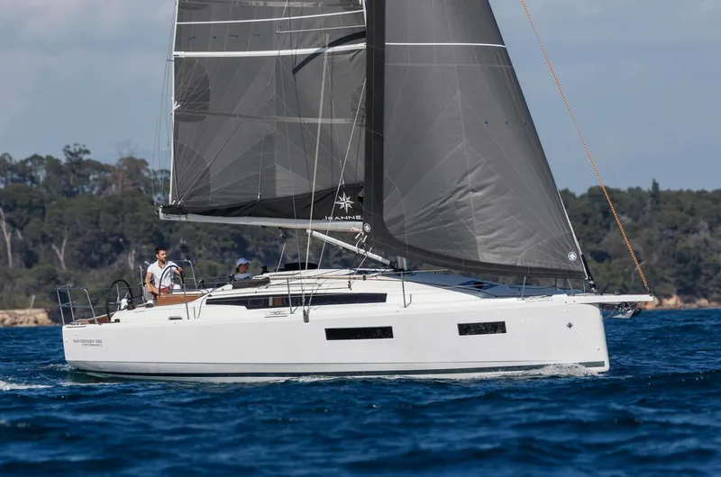  Yacht Photos Pics 2026 Jeanneau Sun Odyssey 350 sailing on open water with black sails.