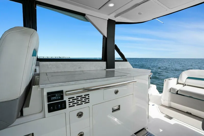 Over The Top Yacht Photos Pics 2021 Regal 36 yacht interior with ocean view, featuring sleek white cabinetry and seating.