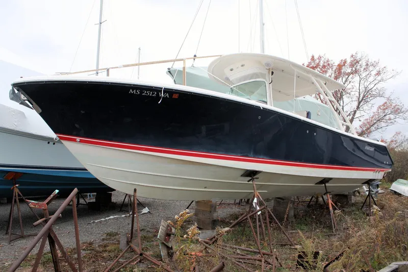  Yacht Photos Pics 2013 Pursuit ST 310 Sport boat on stands, black hull, red stripe, outdoor storage.