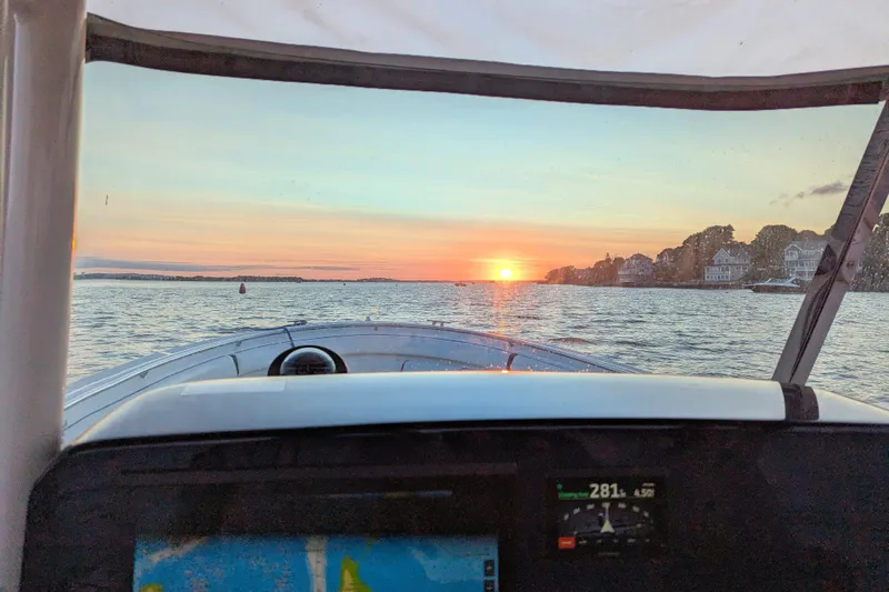  Yacht Photos Pics 2013 Pursuit ST 310 Sport boat navigating at sunset, scenic waterfront view.