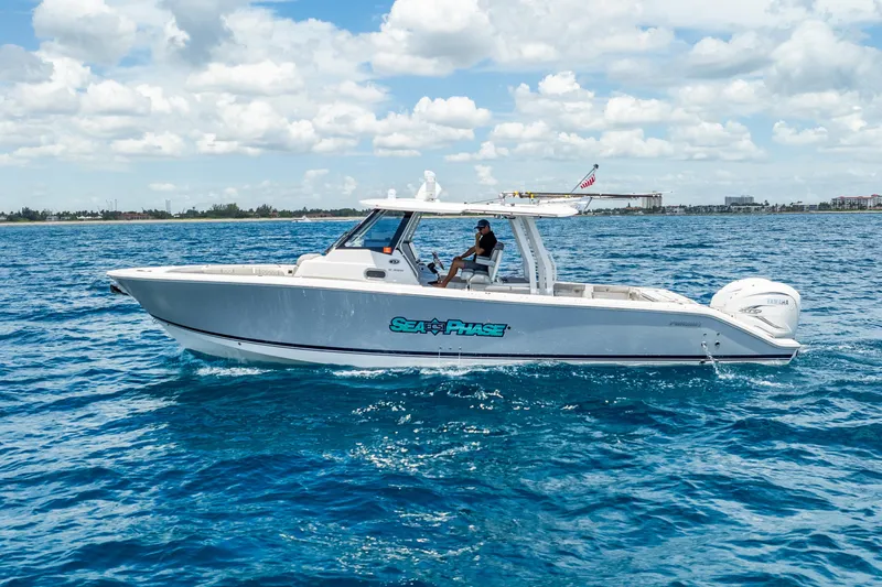Sea Phase Yacht Photos Pics 2024 Pursuit S 358 Sport boat cruising on blue ocean under cloudy sky.