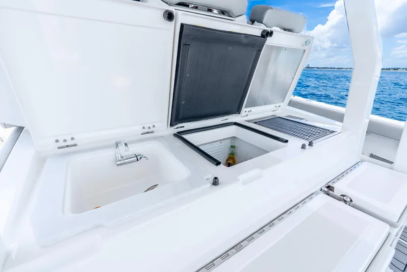 Sea Phase Yacht Photos Pics 2024 Pursuit S 358 Sport boat with open storage compartments and sink, ocean view.